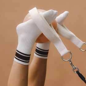 White socks with black pilates stripes and a dog leash on a brown background
