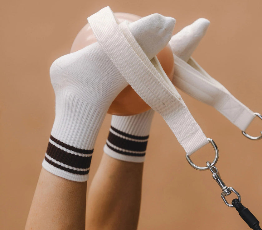 White socks with black pilates stripes and a dog leash on a brown background